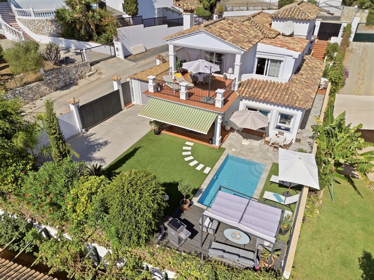 Aerial view of a villa with a private swimming pool, terrace, outdoor seating area, and lush green gardens.