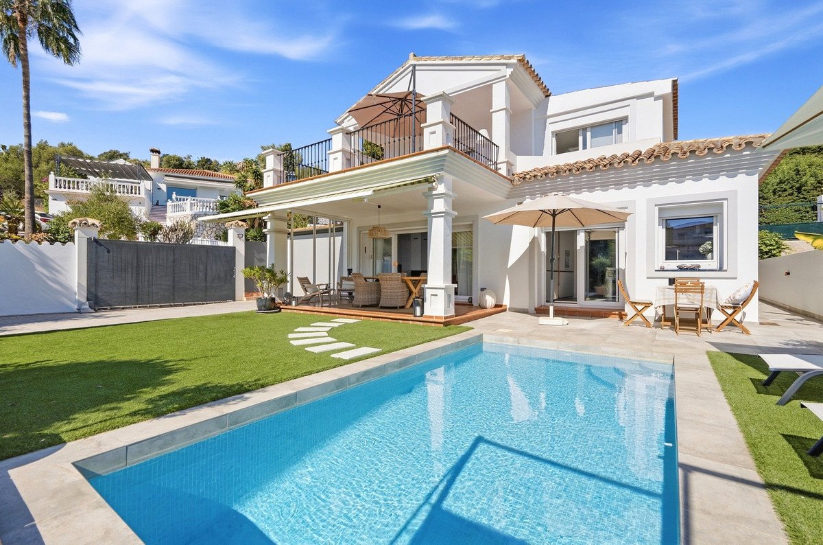 Modern villa with swimming pool, patio with outdoor dining furniture, and a well-maintained garden on a sunny day.