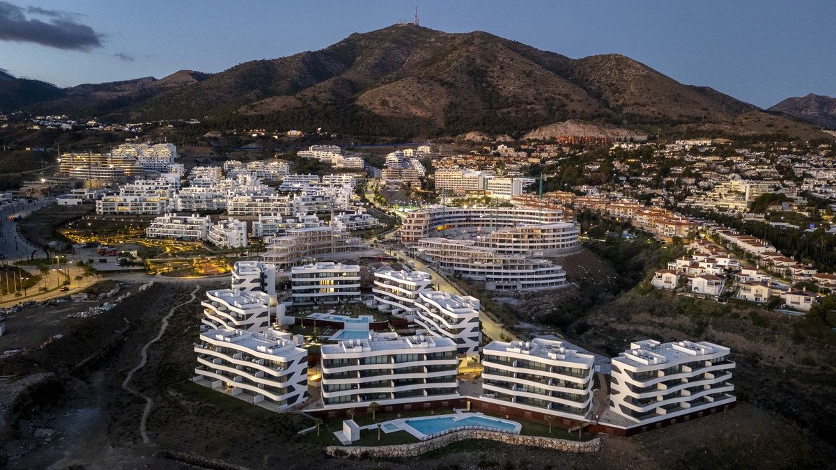 Aerial view of modern apartment complex with mountain backdrop at dusk