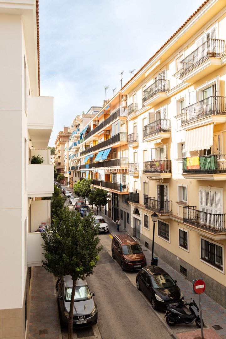 Urban apartment building with balconies overlooking a street with parked cars