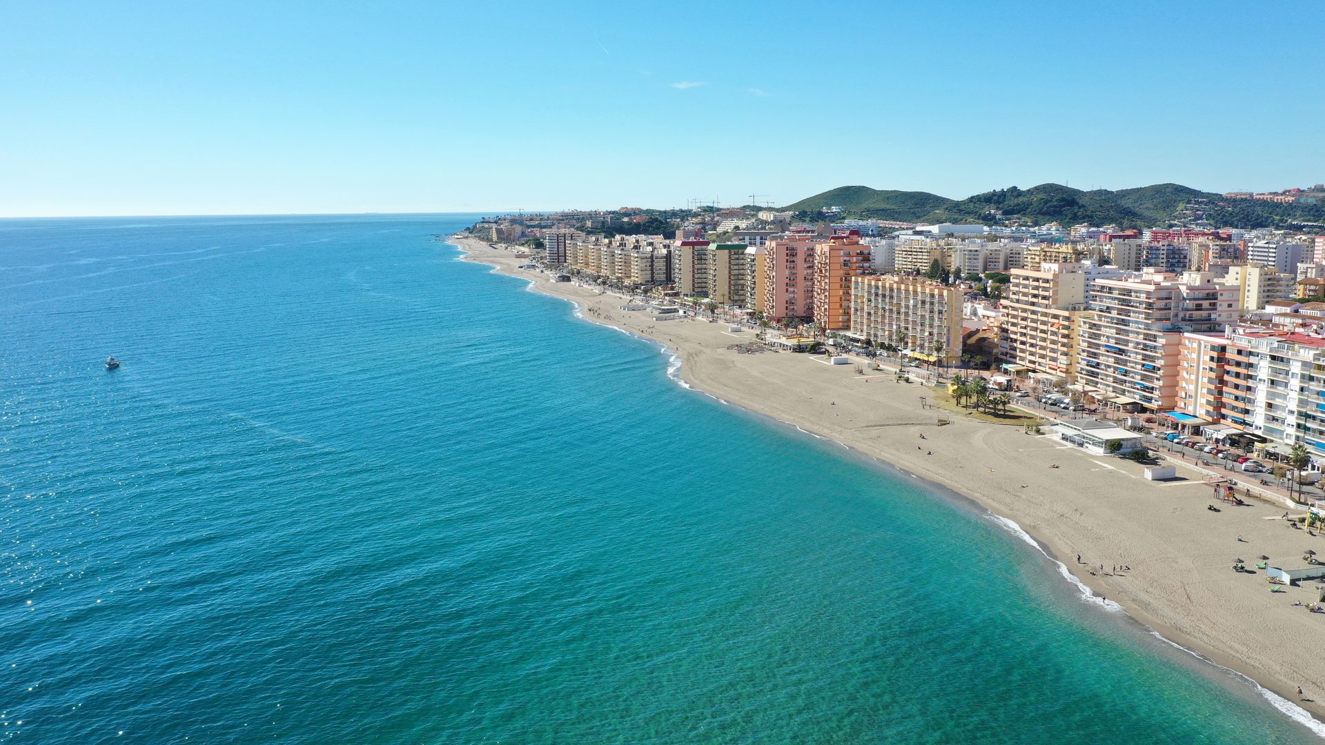 Aerial view of a coastal city with a sandy beach and clear blue water.