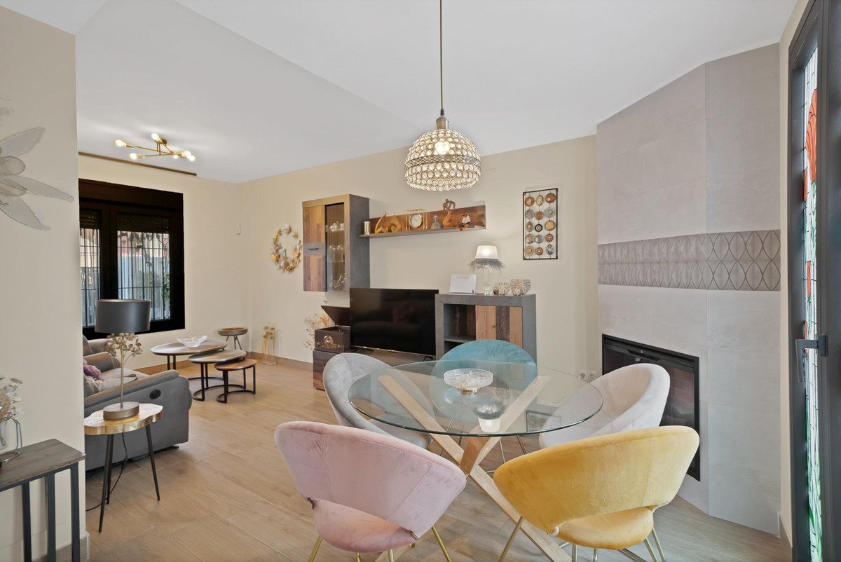 Spacious living and dining area with a glass table, colorful chairs, fireplace, and a TV stand.