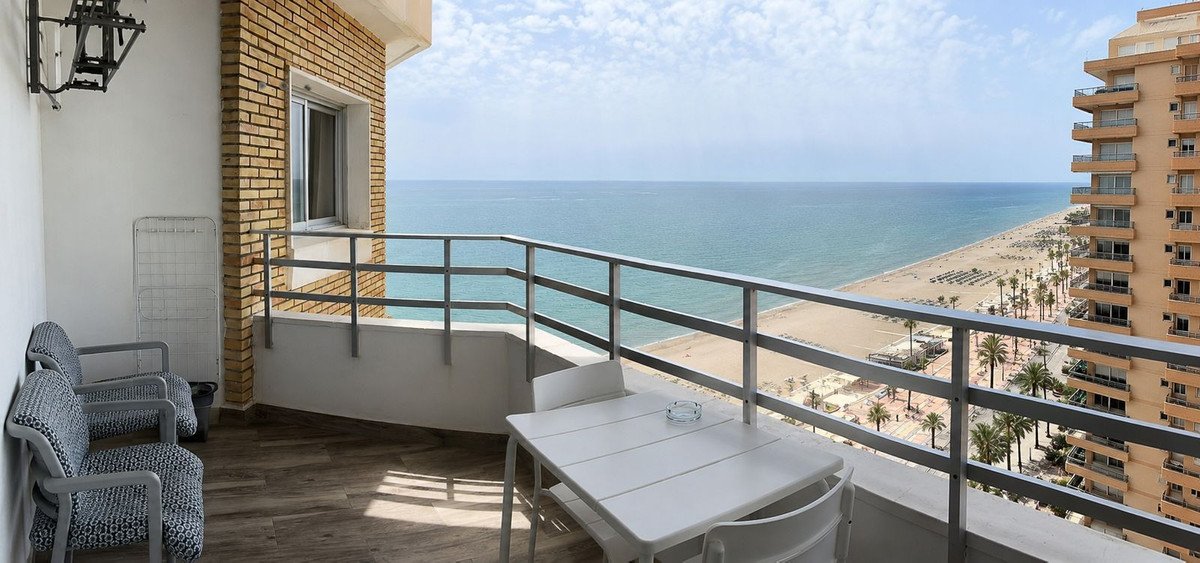Spacious balcony with table, chairs, and stunning ocean and beach views from a high floor.