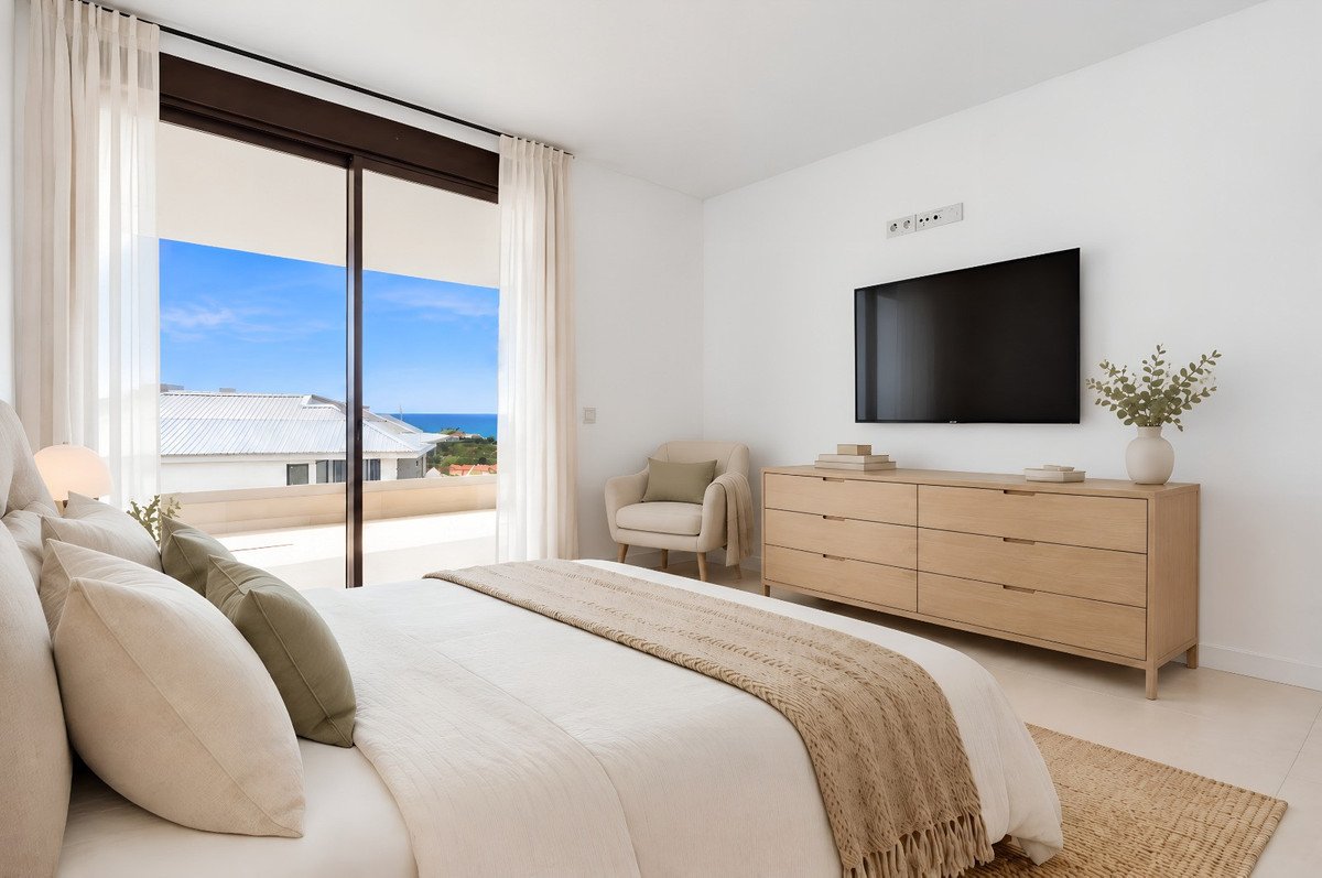 Modern bedroom with a large window offering a sea view, a TV, and a comfortable armchair.