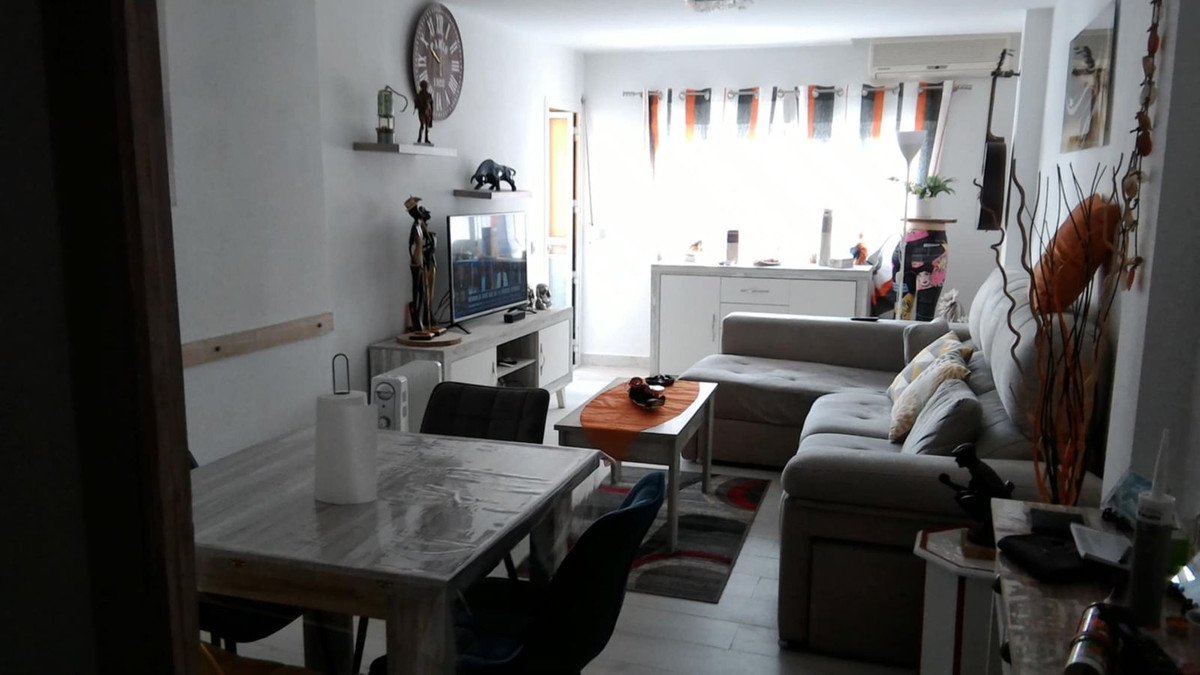 Cozy living room featuring a sectional sofa, coffee table, dining table, and a television on a console.
