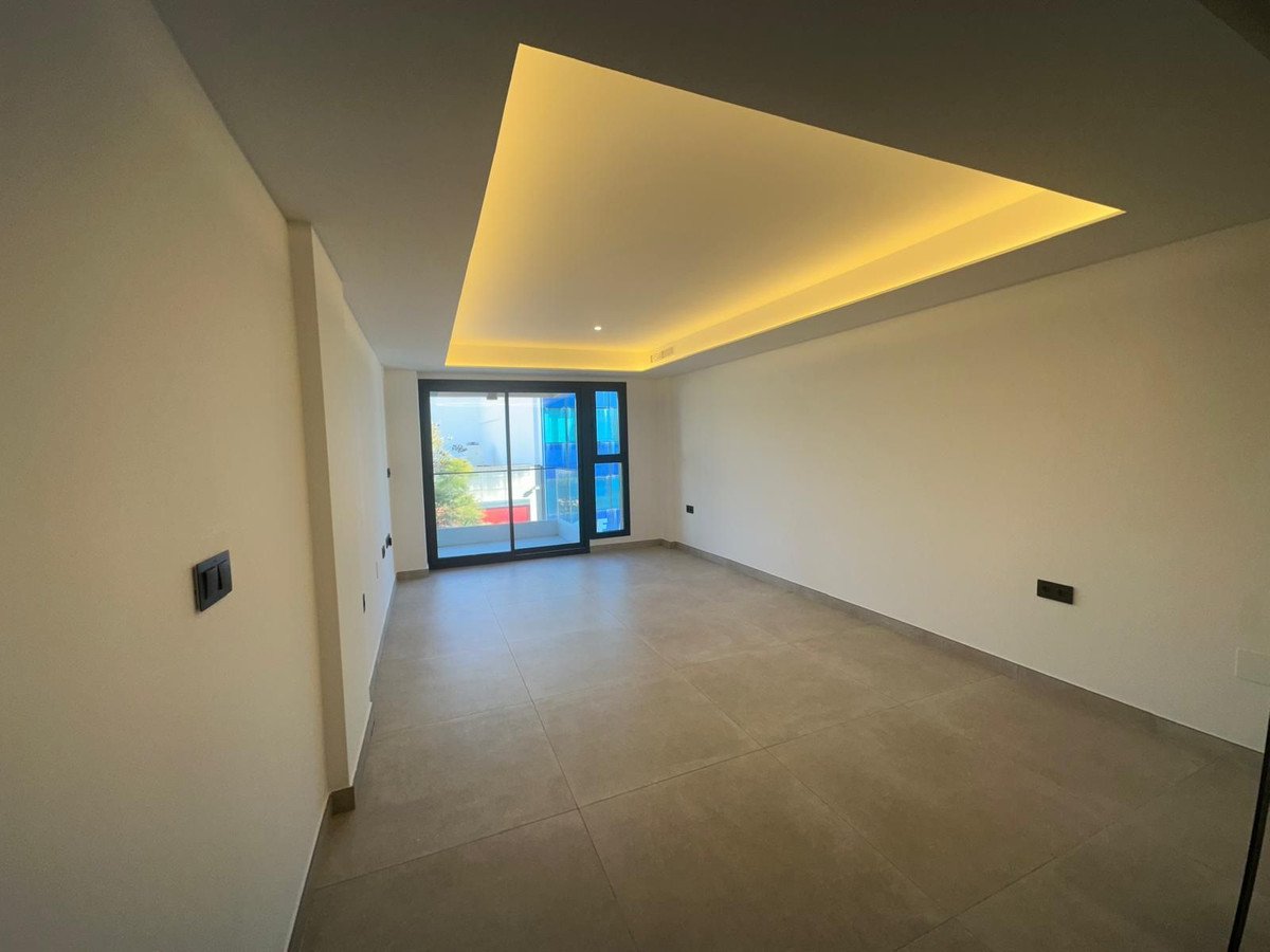 Empty, modern interior room with large windows showing an outdoor view and decorative ceiling lighting.