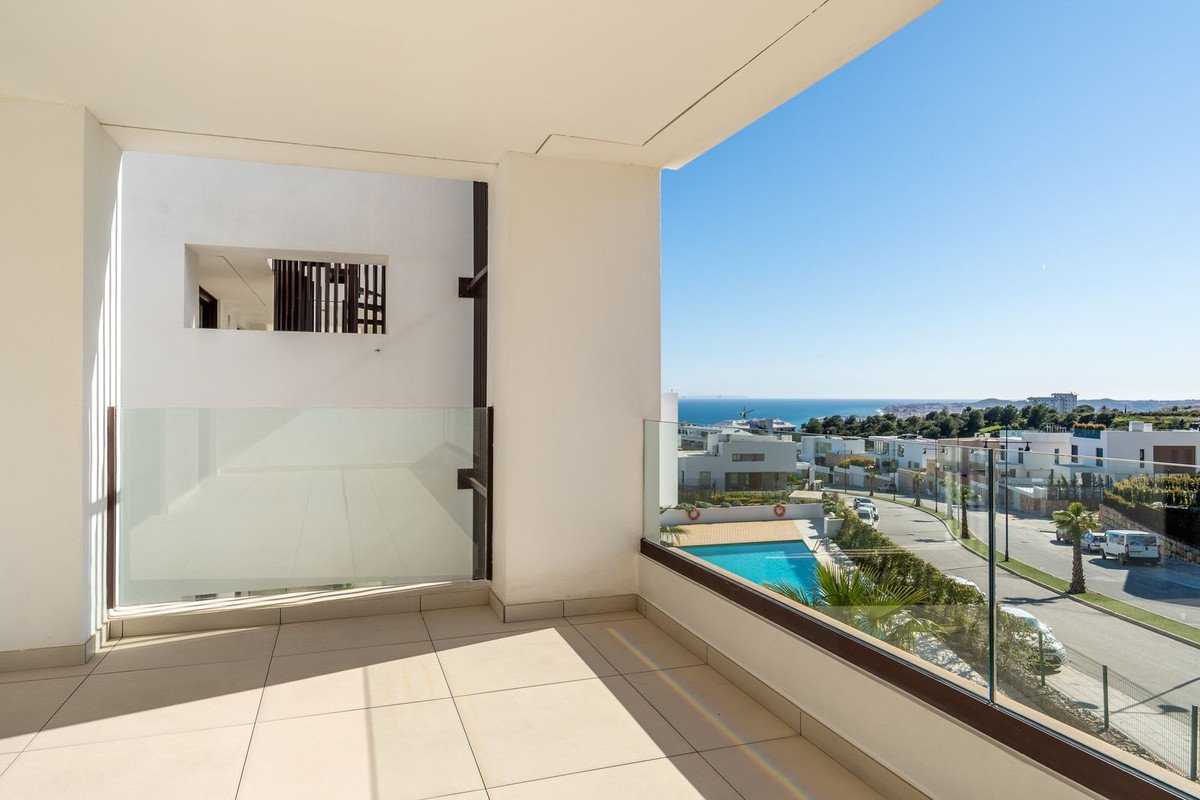 Modern balcony with glass railing, tiled floor, and ocean view overlooking pool and residential area.