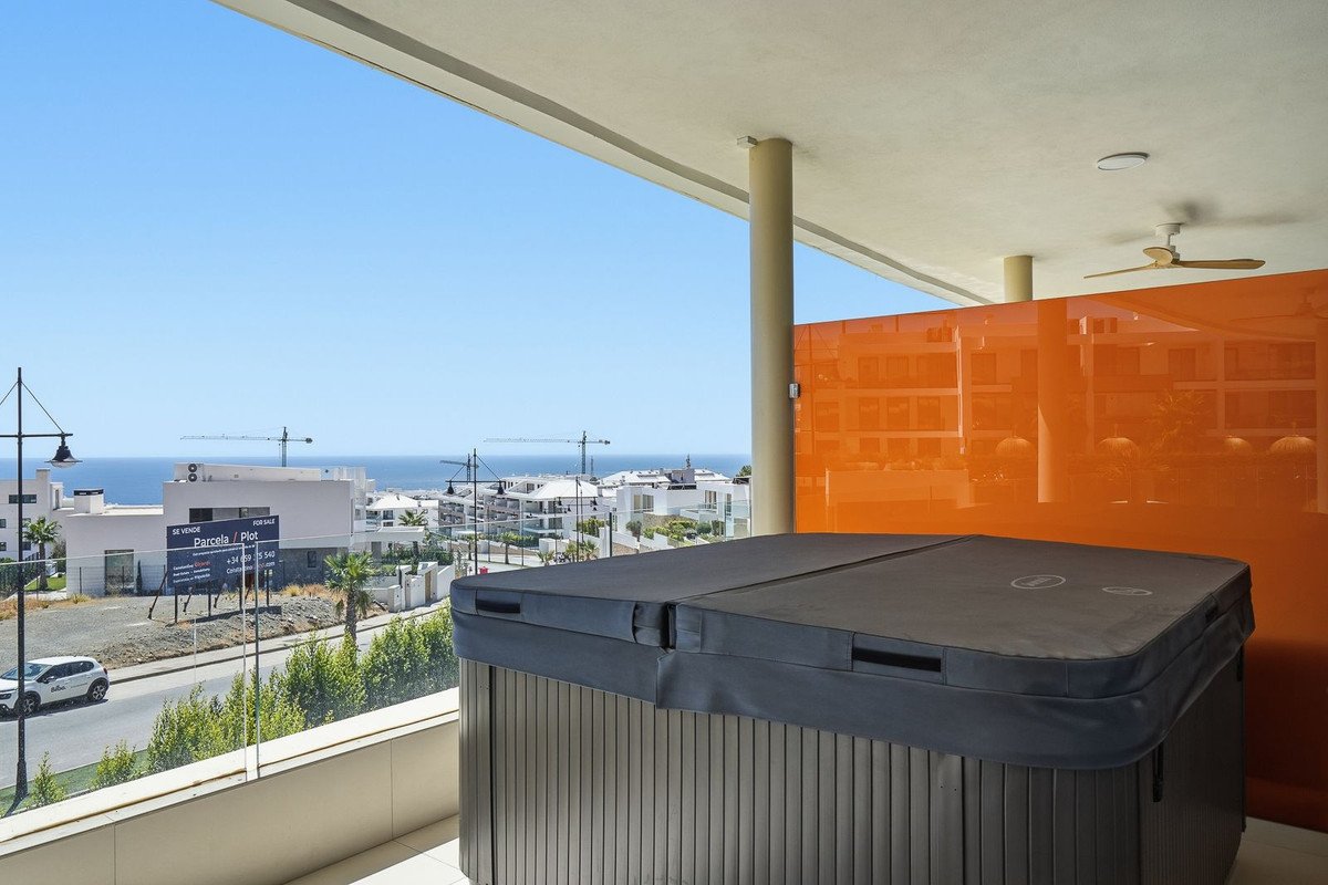 Balcony with a covered hot tub, offering a panoramic view of the sea and coastal town.