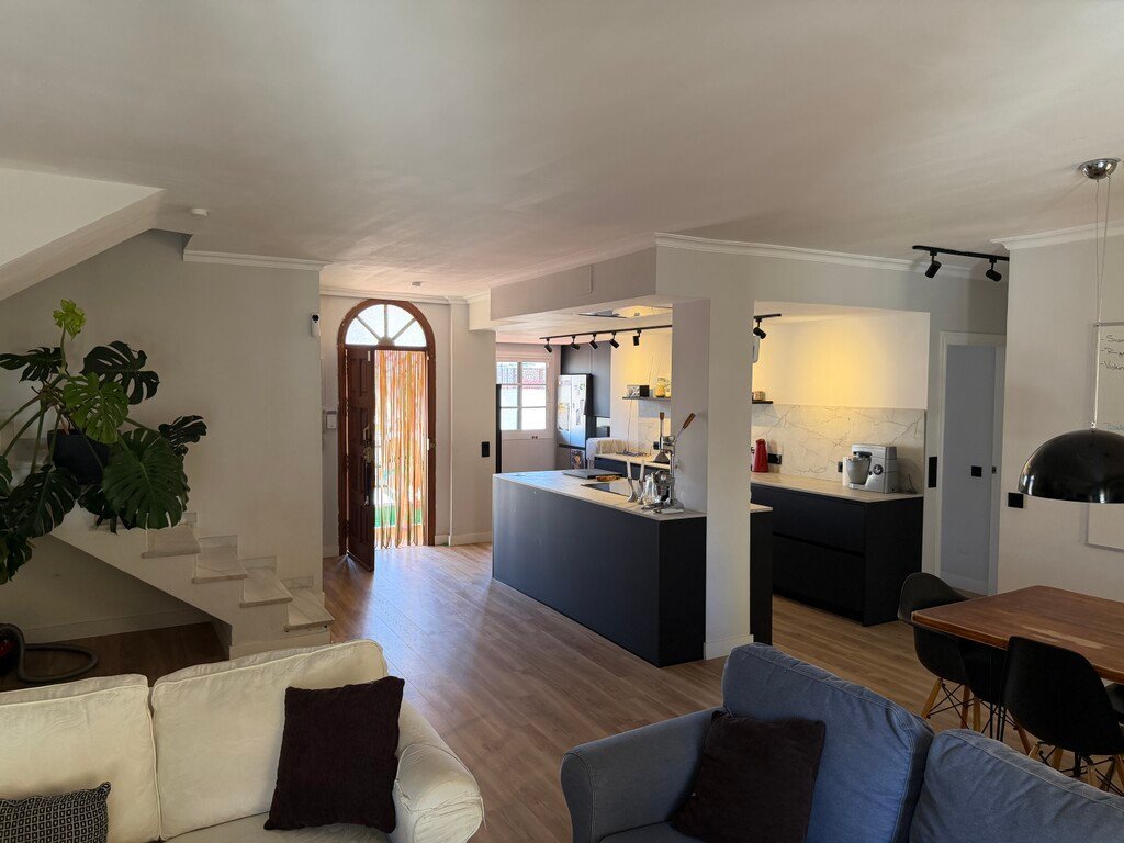 Spacious open-plan living area with modern kitchen, dining table, and staircase leading to the upper floor.