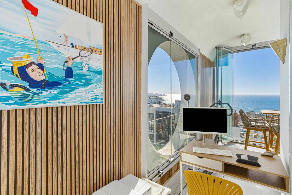 Home office with ocean view, wooden walls, glass doors, and a colorful mural.