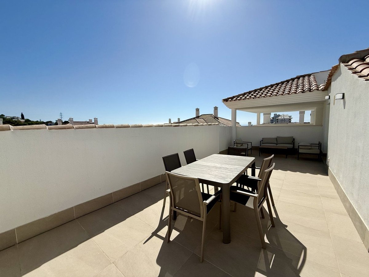 Spacious terrace with outdoor dining table and chairs, lounge seating area, and rooftop views under a clear blue sky.