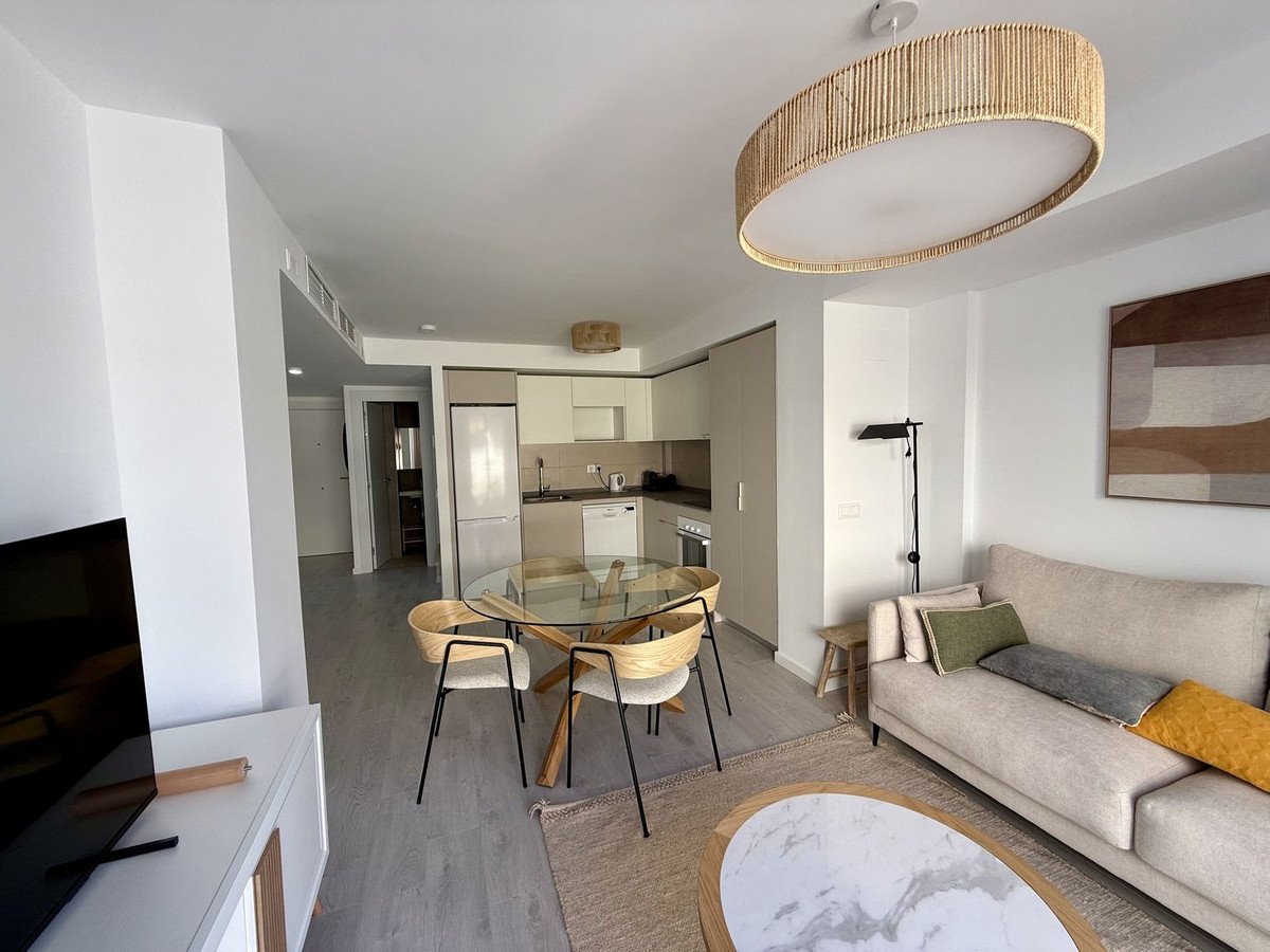 Modern open-plan living, dining, and kitchen area with a sofa, dining table, and modern appliances.