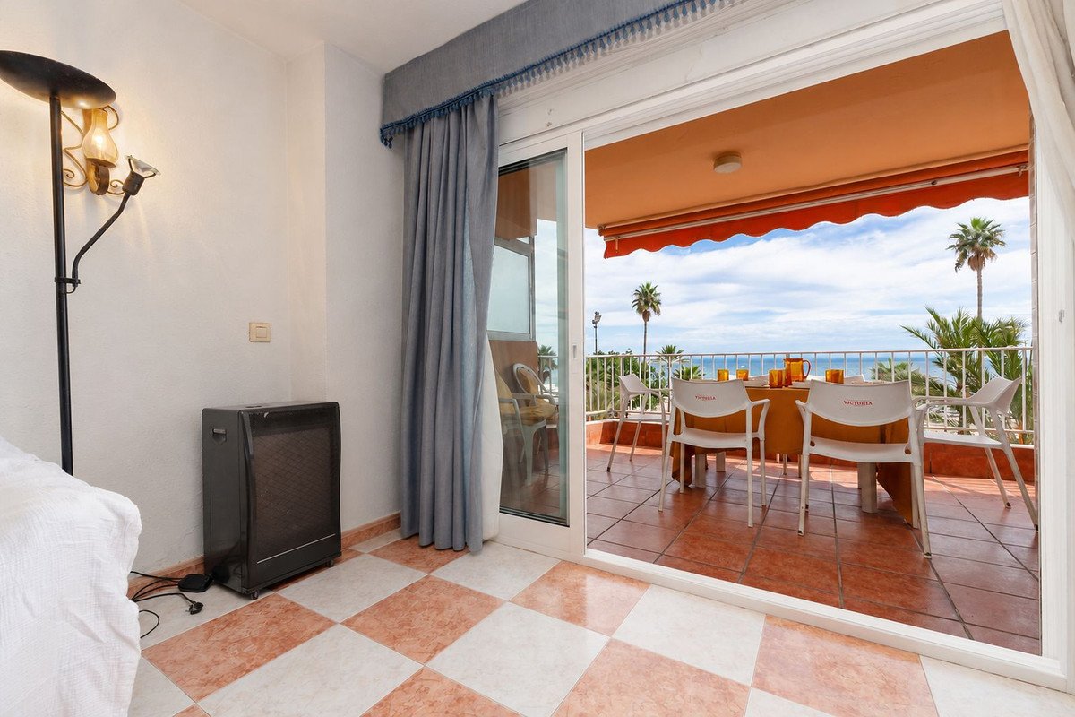 Spacious balcony with a table and chairs offering a stunning sea view and palm trees.