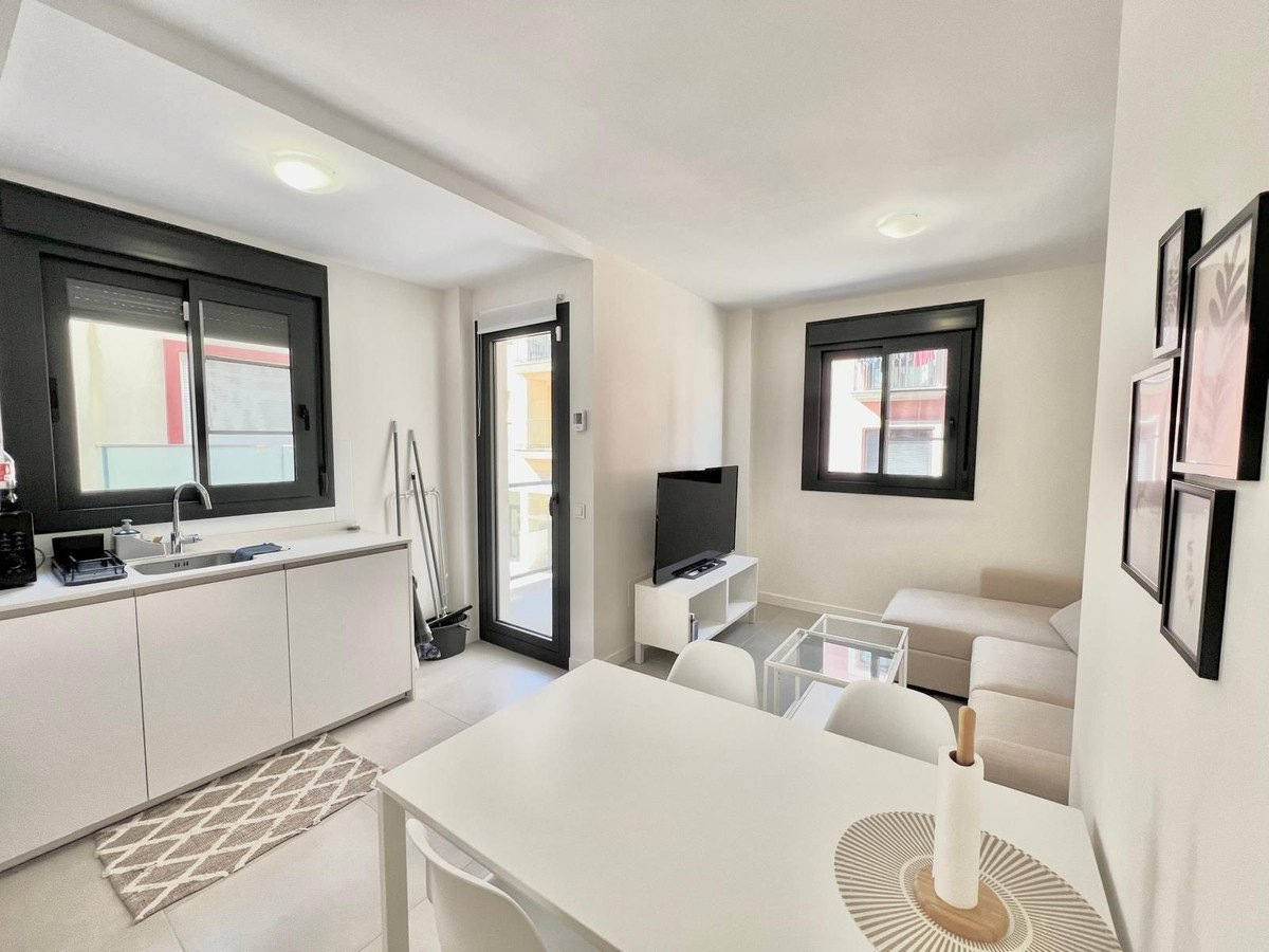 Modern open-plan living and dining area with kitchen, sofa, and glass coffee table.