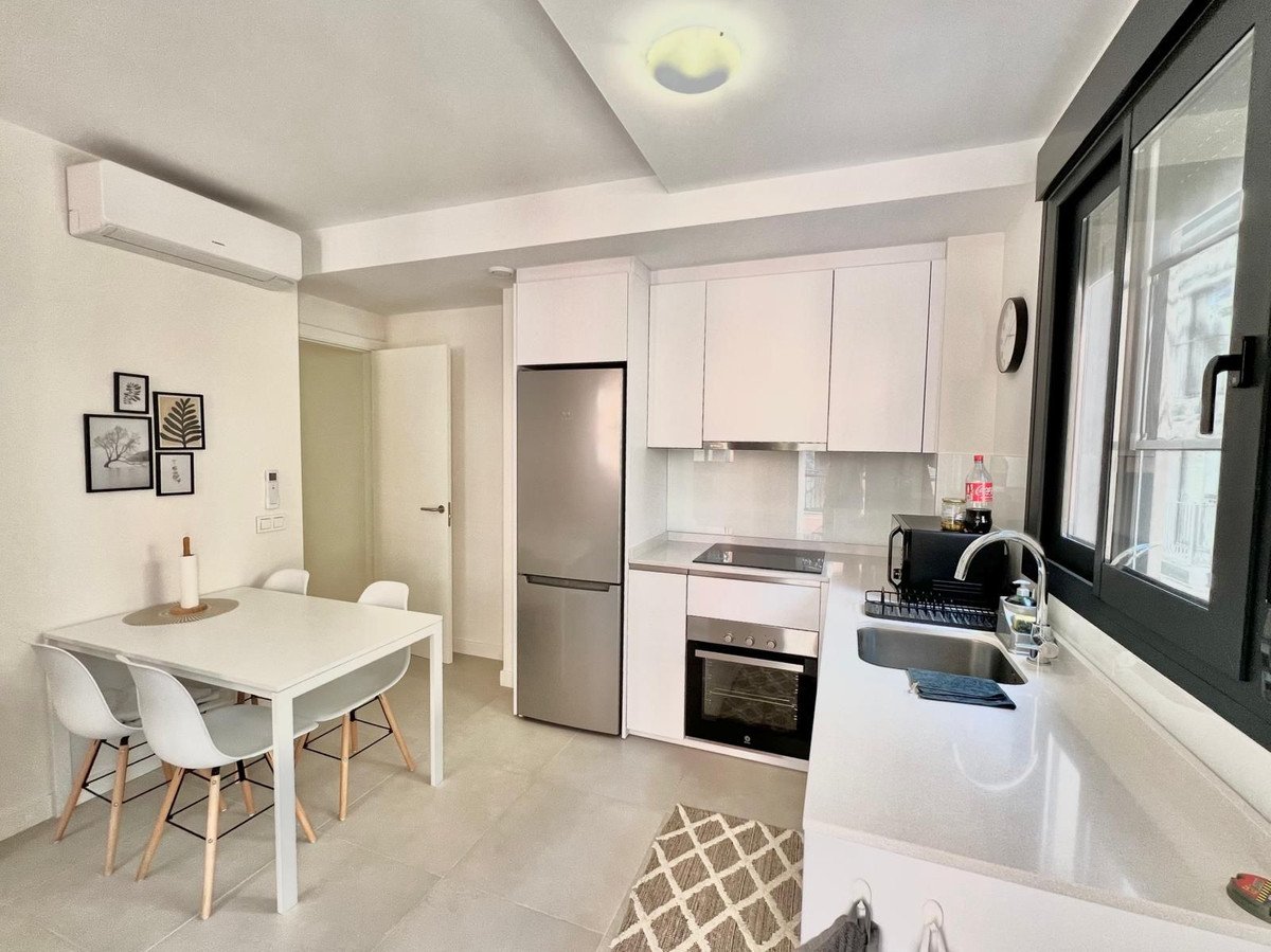Modern kitchen and dining area with white cabinets, stainless steel fridge, and dining table