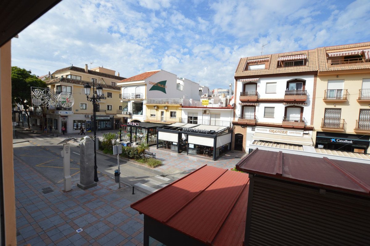 View of town square with buildings, shops, and paved plaza from balcony