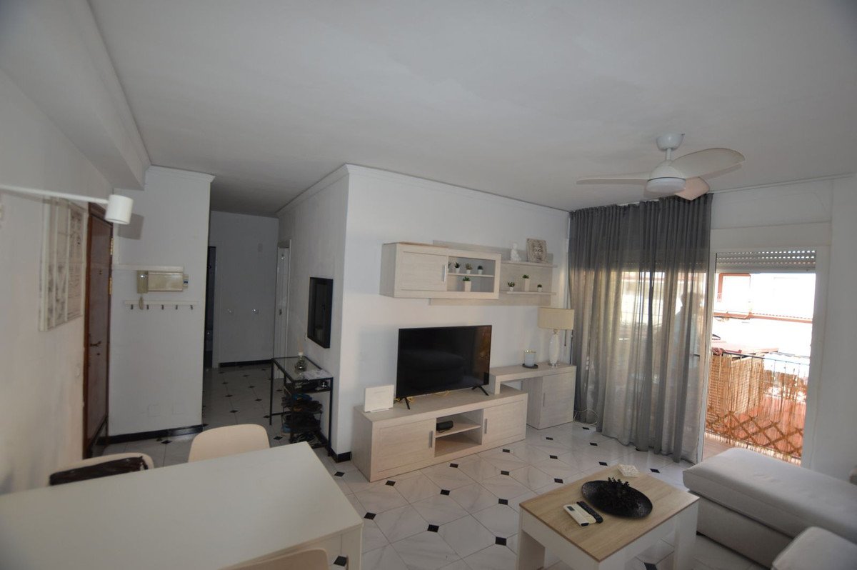 Living room with tiled floor, TV, sofa, and balcony view through sliding doors