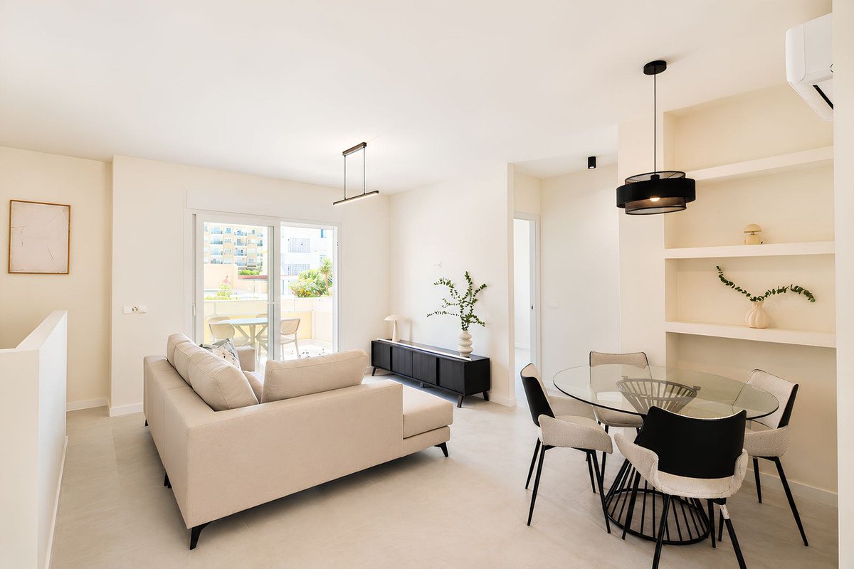 Modern open-plan living and dining room with glass table, beige sofa, and large windows