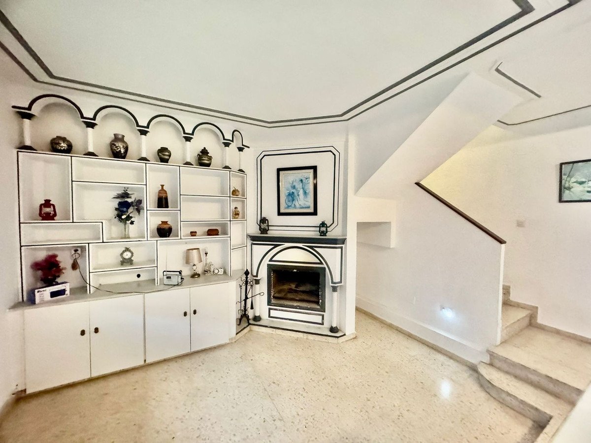 Living room with decorative shelving, fireplace, and a staircase leading upstairs.