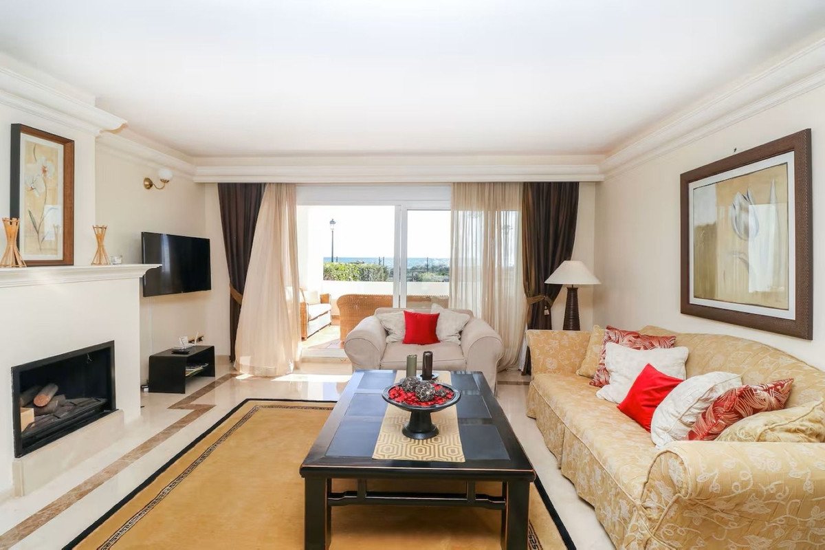 Living room with fireplace, comfortable seating, and large balcony doors offering a sea view.