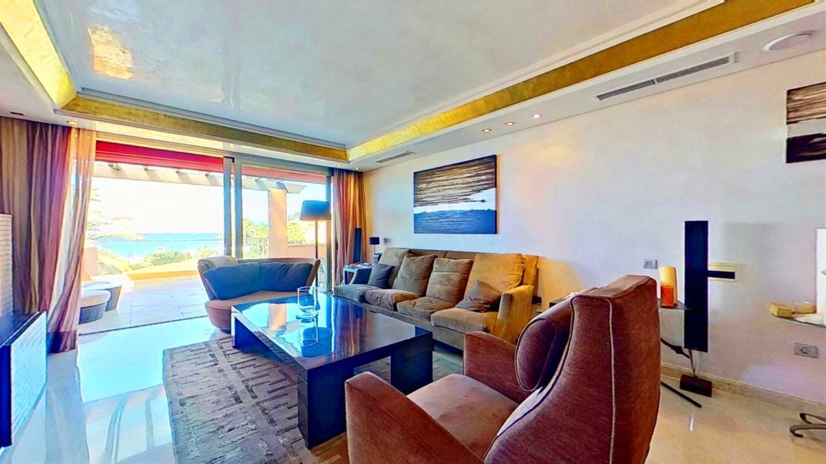 Spacious living room with comfortable sofas, a large coffee table, and sliding doors opening to a terrace with a sea view.