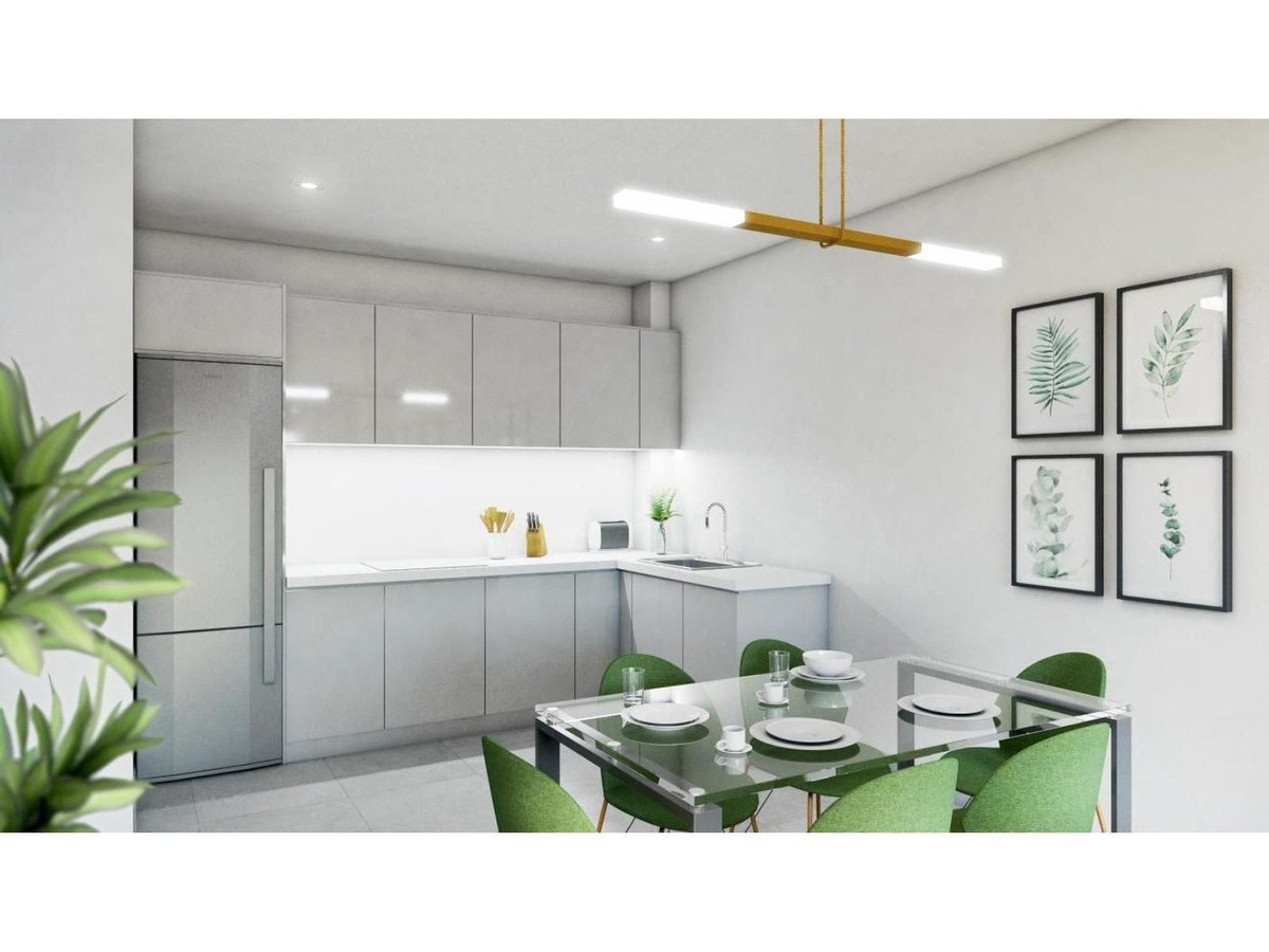 Modern kitchen with dining area, white cabinets, green chairs, and artwork.