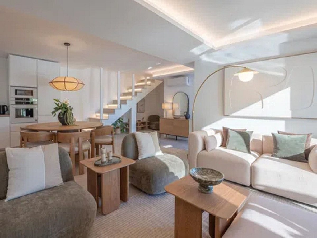 A modern living and dining area with a kitchen and stairs, featuring stylish furniture and contemporary decor.