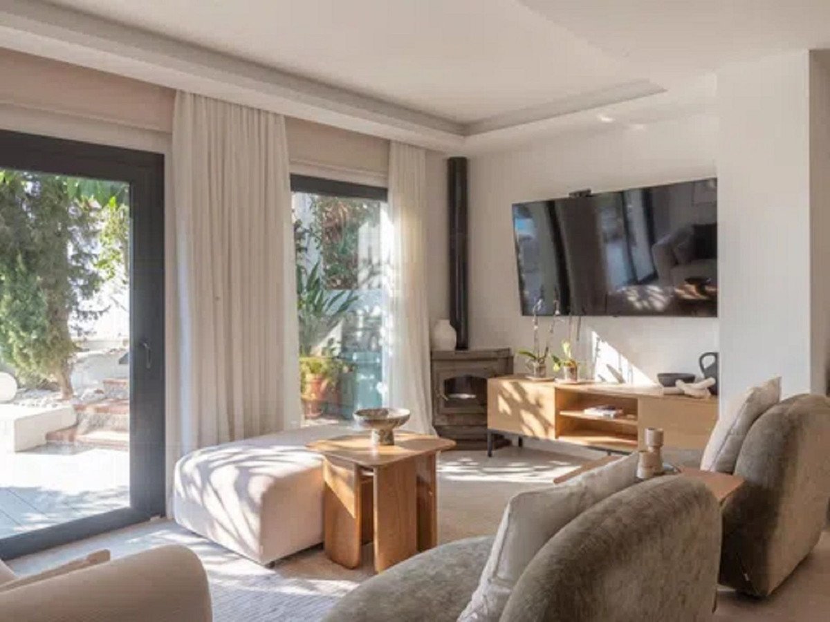 Modern living room with a large TV, fireplace, and patio doors leading to an outdoor seating area.