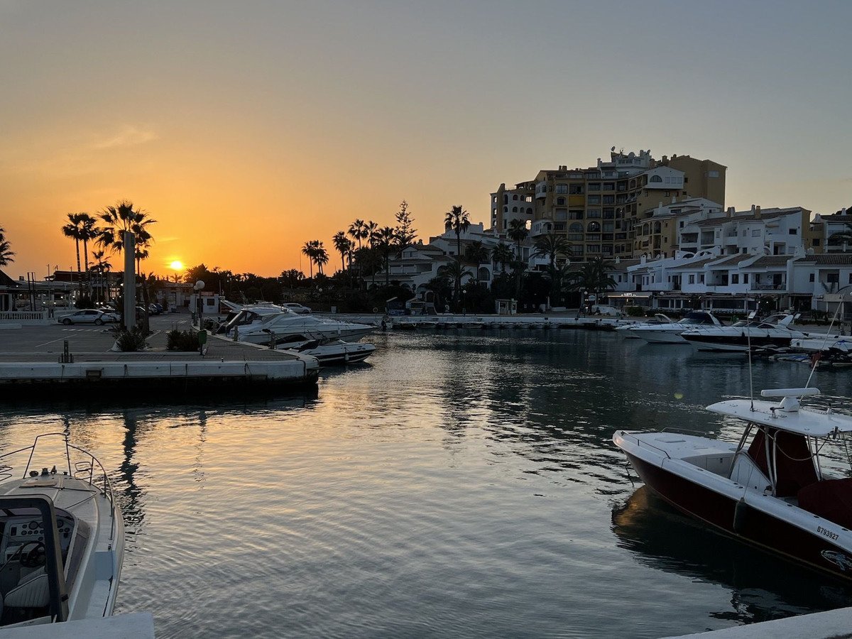 A beautiful sunset over a marina with boats docked and residences in the background.