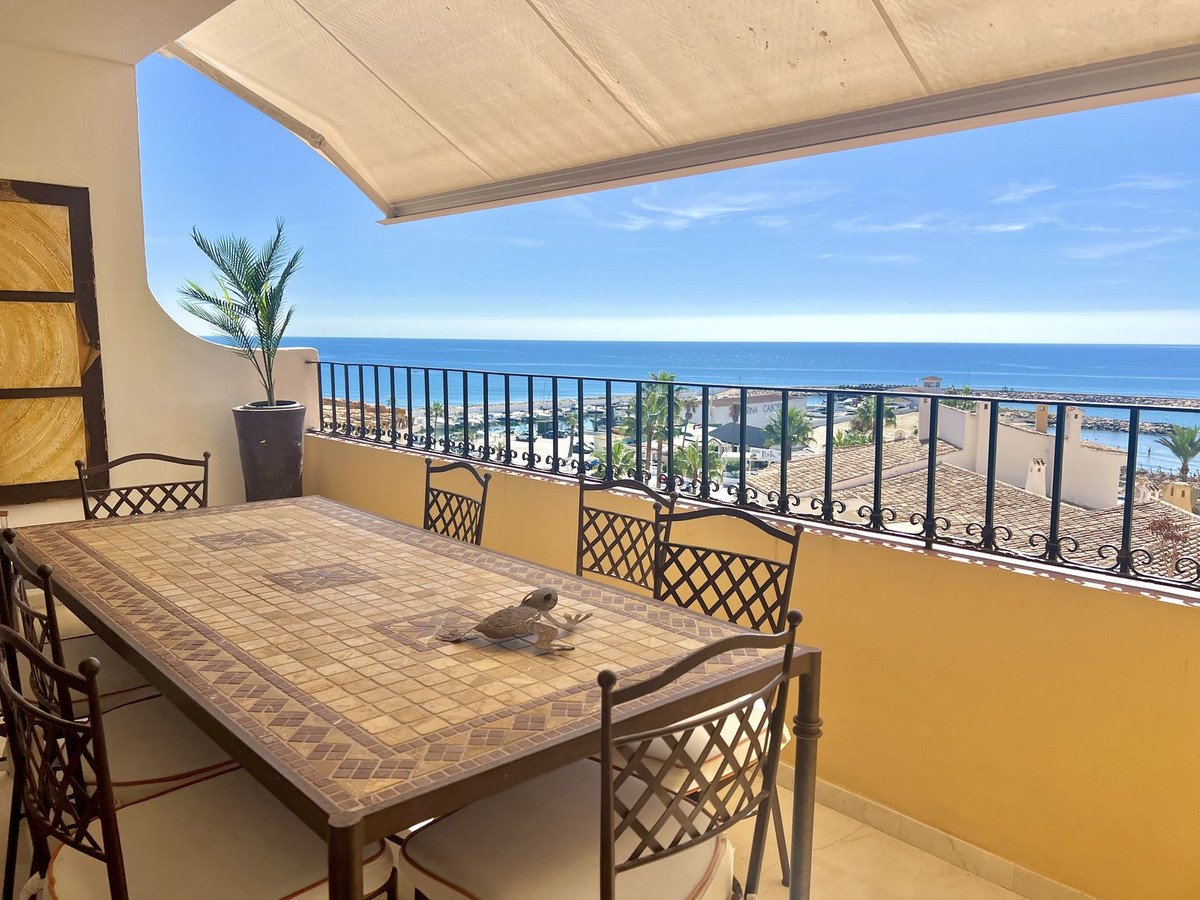 Spacious terrace with dining table and chairs, offering a stunning sea view and distant coastline.