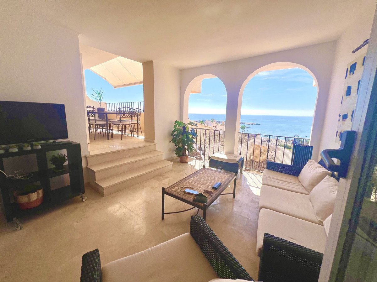 Spacious living area with sofa, coffee table, and balcony access offering a stunning sea view and an outdoor dining terrace.