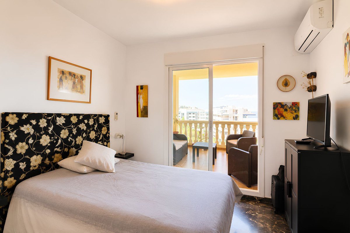 Bedroom with a king-size bed, floral headboard, and a balcony with chairs and a sea view.