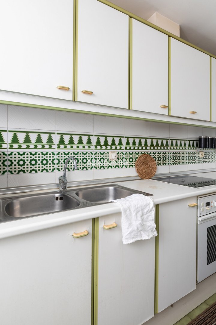 Modern kitchen with white cabinets, green tile backsplash, and stainless steel sink