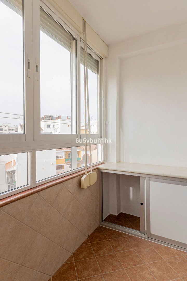 Interior view of a room with large windows offering a city view, built-in storage, and tiled floors.