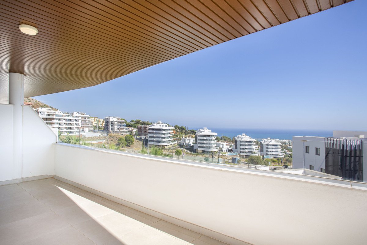 Modern balcony with ocean view, wooden ceiling, and nearby buildings.