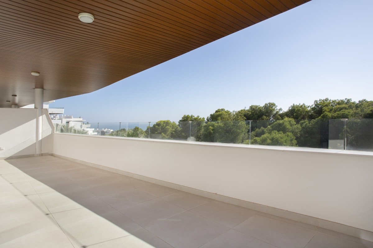 Modern balcony with sea view, glass railing, and wooden ceiling