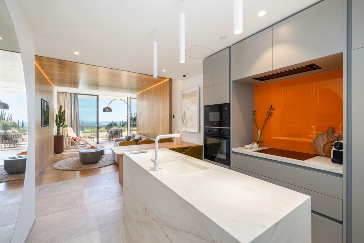 Modern open-plan living space with a sleek kitchen, island, and comfortable seating area with a sea view.