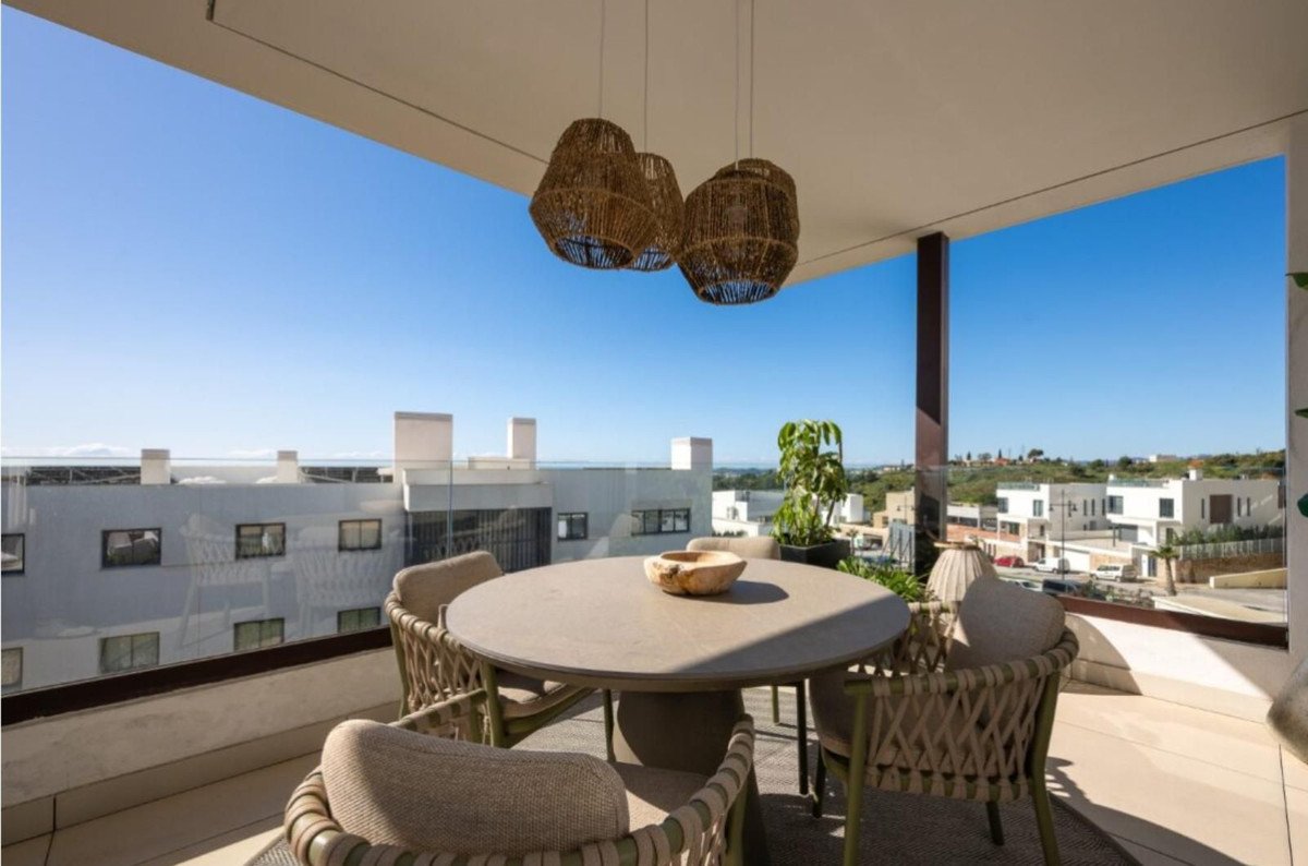 Modern terrace dining set with chairs and table, offering a view of surrounding buildings and hills under a clear blue sky.