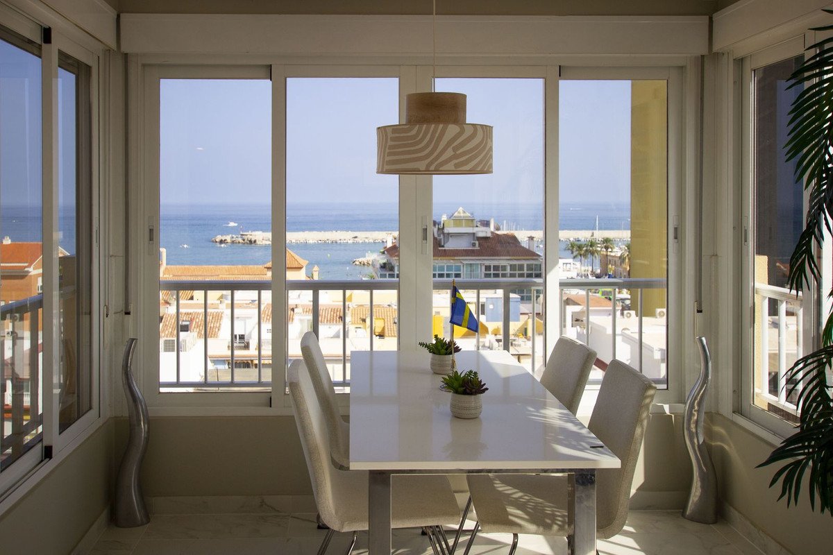 Dining area with a table and chairs, offering a stunning sea view with a balcony overlooking the town and ocean.