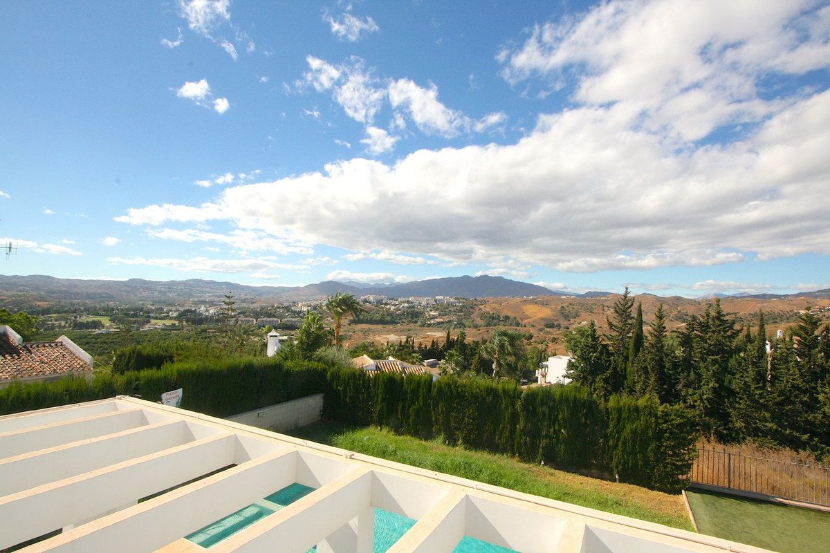 View from a villa terrace overlooking a valley, with mountains in the distance and a glimpse of a swimming pool.