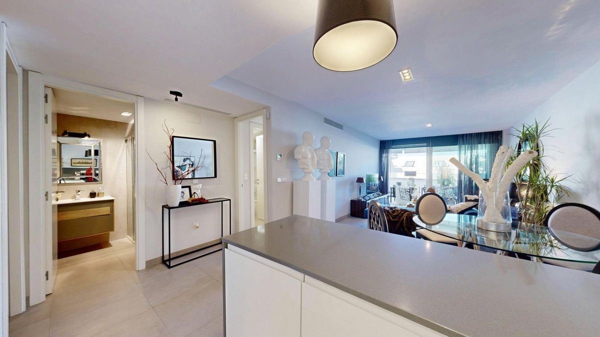 Modern living room with a dining area, large windows, and a view of an outdoor space. Includes busts and plants.
