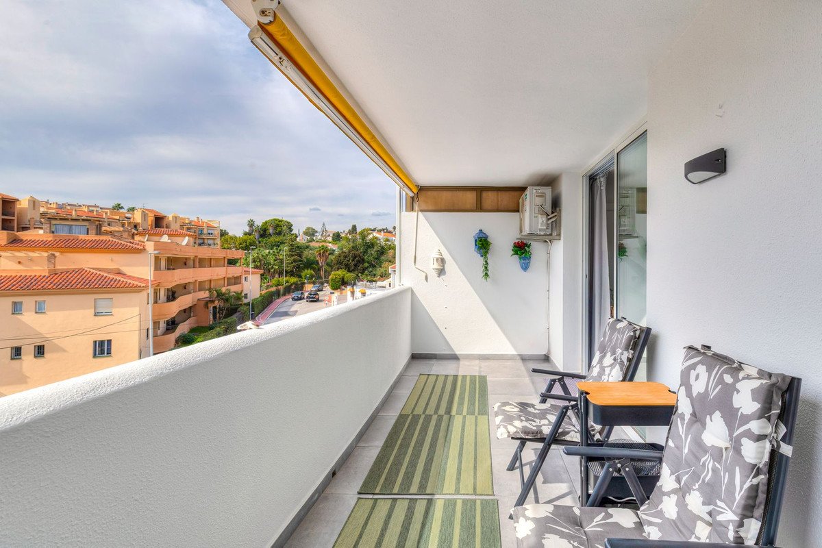 Balcony with two chairs, small table, and a view of nearby buildings