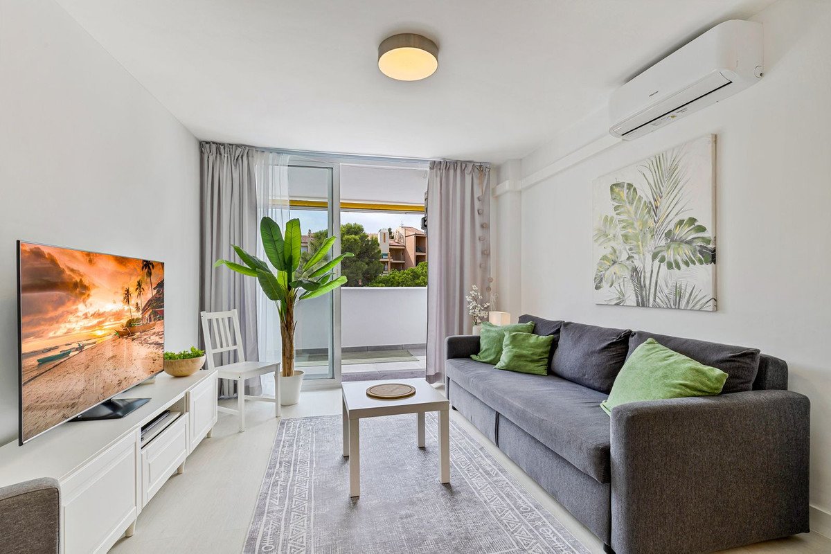 Modern living room with grey sofa, green pillows, TV, and balcony view