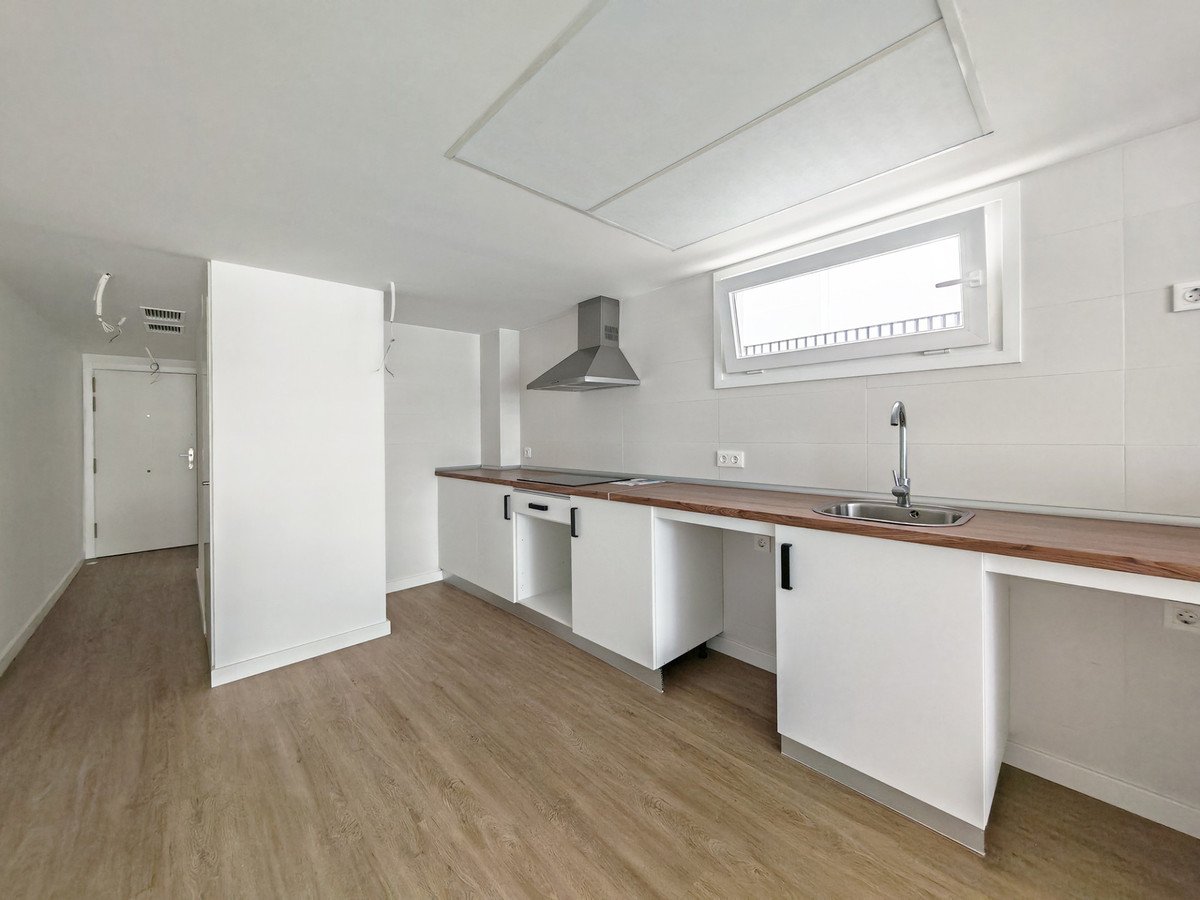 Modern kitchen with white cabinets, wooden countertops, sink, and a window.