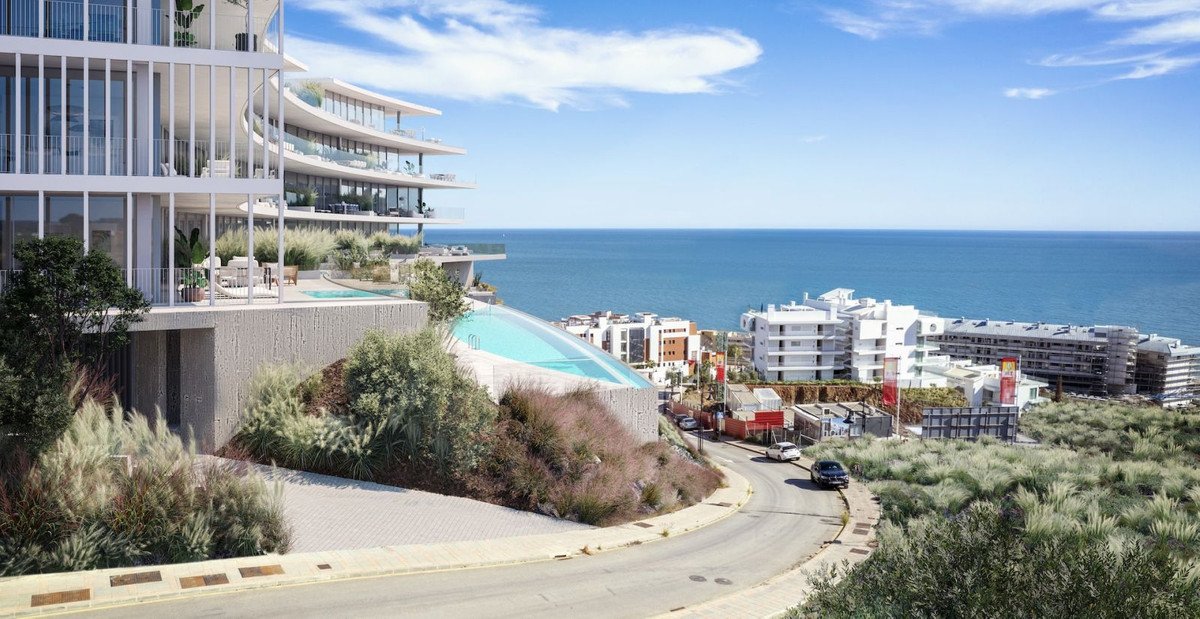 Modern apartment building with balconies, infinity pool, and sea view.