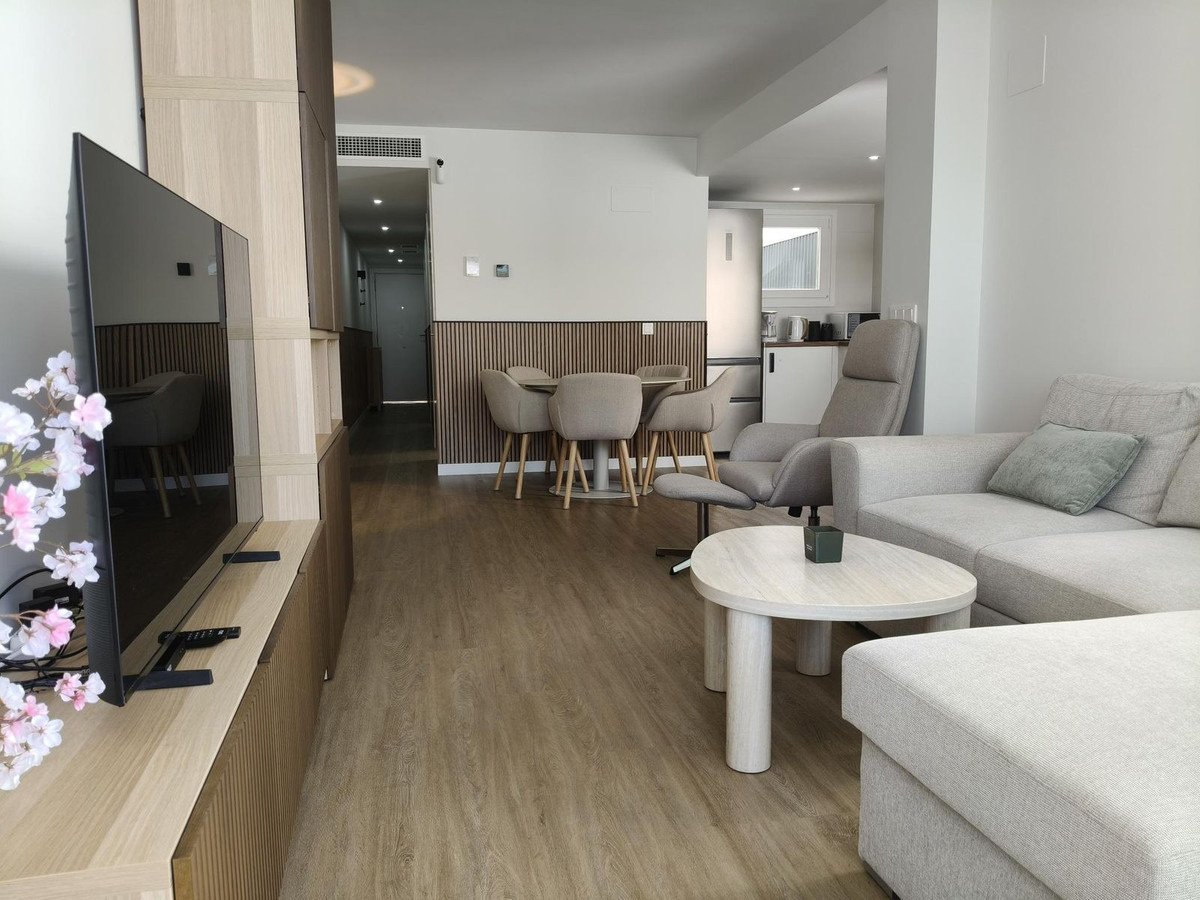 Modern living and dining area with a sectional sofa, armchair, coffee table, and dining set visible kitchen in-built entertainment unit.