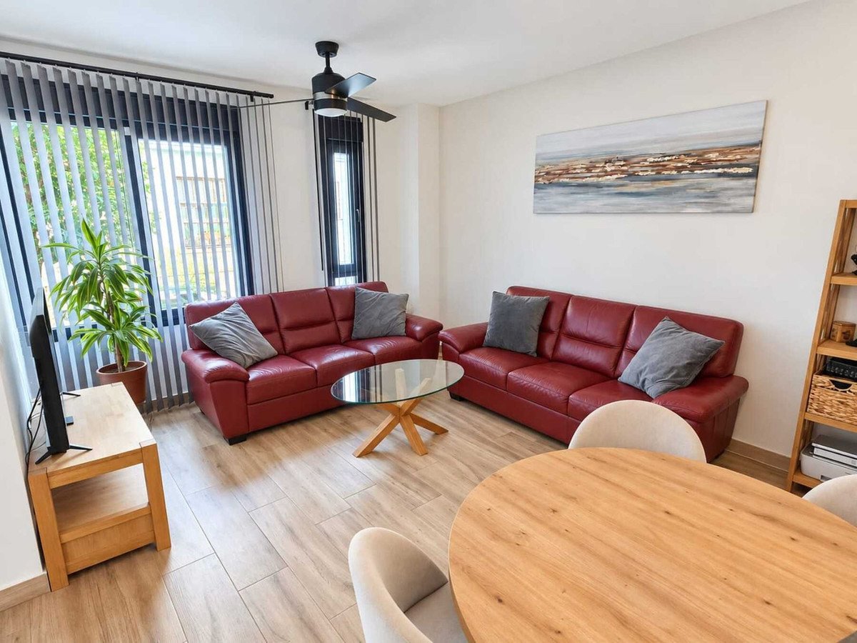 Modern living room with two red leather sofas, a glass coffee table, and a wooden dining table.
