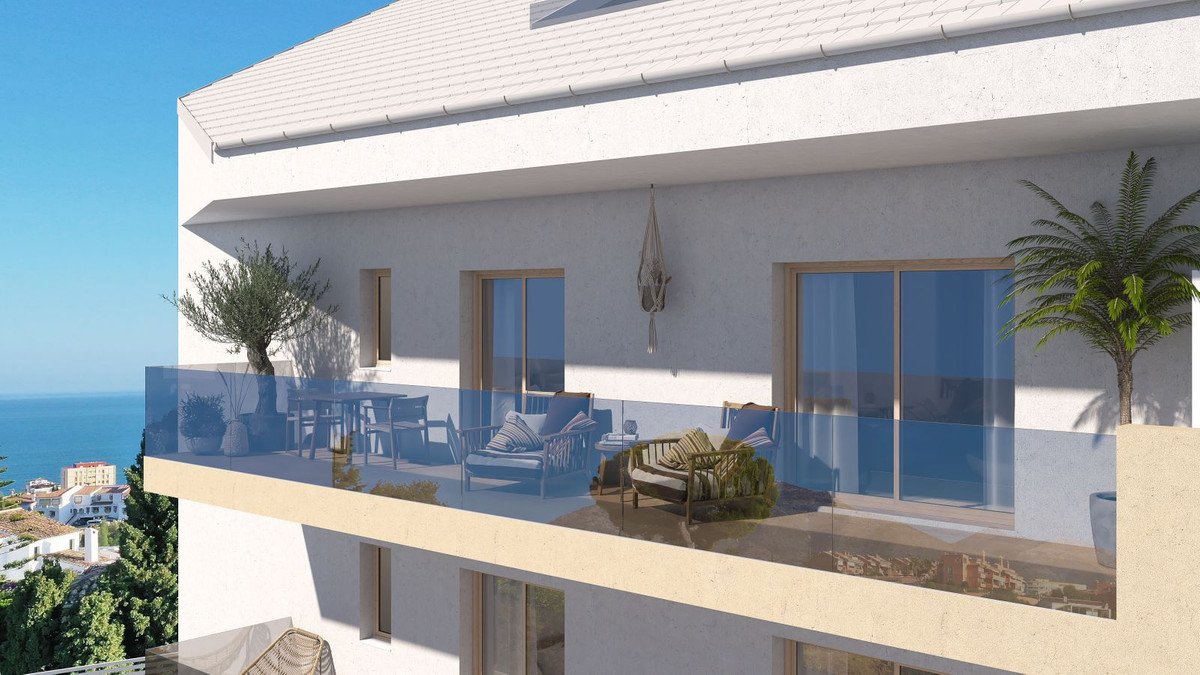 Modern apartment balcony with sea view, outdoor seating, dining table, and glass railings.