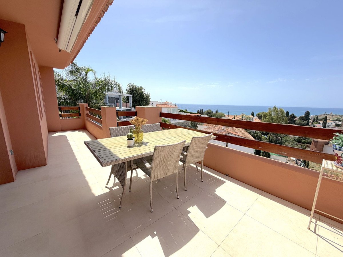 A spacious terrace with a dining table and chairs offers a beautiful sea view and a sunny ambiance.