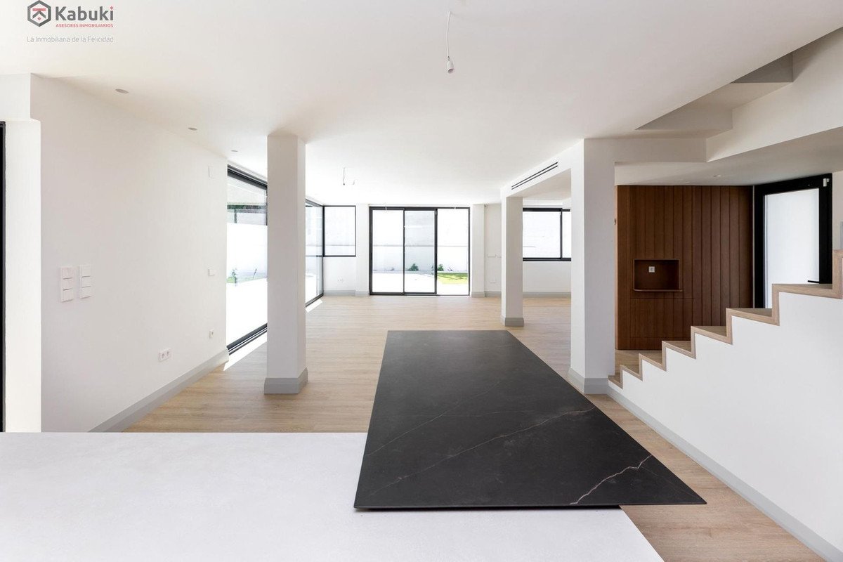 Spacious modern living room with large windows offering garden views and a stylish black island countertop.